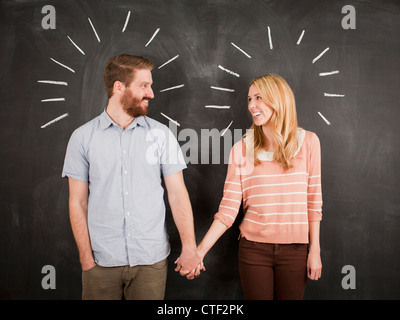 Coppia giovane con blackboard in background, studio shot Foto Stock