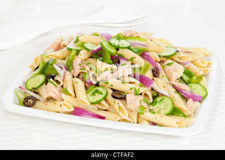 Un insalata di pasta con un pesto di basilico medicazione, tonno, olive, cipolla rossa, il cetriolo e il peperone verde, cosparsa di prezzemolo. Foto Stock