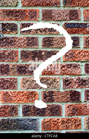 Muro di mattoni con tre punti di domanda scritta su di esso Foto Stock