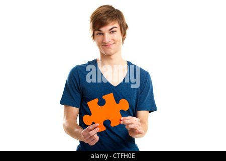 Giovane uomo in possesso di un pezzo di puzzle isolati su sfondo bianco, del concetto di soluzione Foto Stock