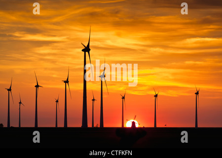 I Paesi Bassi, Eemsmond, Eemshaven, Windturbines e mulino a vento tradizionale. Il tramonto. Foto Stock