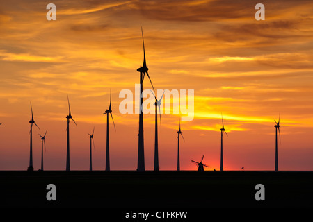 I Paesi Bassi, Eemsmond, Eemshaven, Windturbines e mulino a vento tradizionale. Il tramonto. Foto Stock