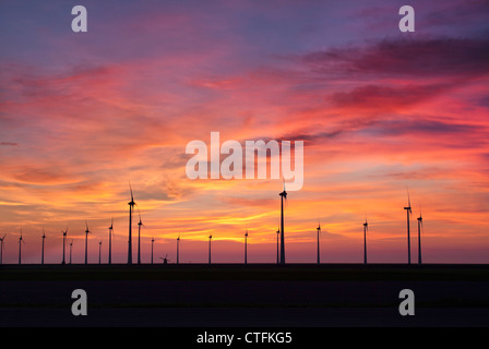 I Paesi Bassi, Eemsmond, Eemshaven, Windturbines e mulino a vento tradizionale. Il tramonto. Foto Stock