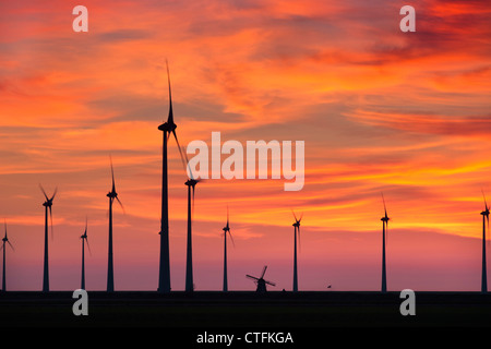 I Paesi Bassi, Eemsmond, Eemshaven, Windturbines e mulino a vento tradizionale. Il tramonto. Foto Stock