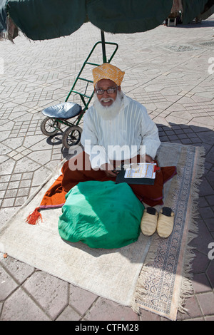 Il Marocco Marrakech chiamato Piazza Djemaa El Fna. Uomo Santo di lettura da libri islamico e il Corano Foto Stock