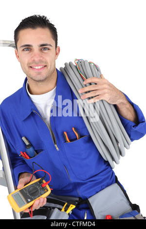 Lavoratore che trasportano i cavi avvolto attorno la sua spalla Foto Stock