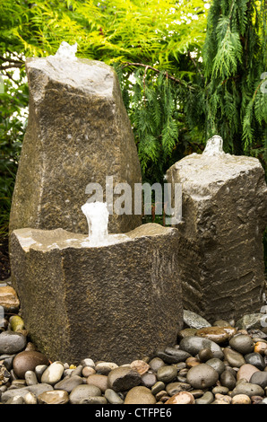 Tre Fontane di roccia gorgogliamento di acqua in un giardino Foto Stock