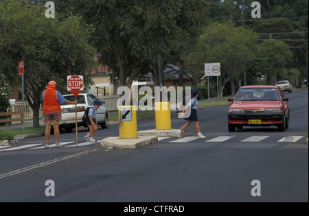 I BAMBINI DELLA SCUOLA PRIMARIA AUSTRALIANA CHE ATTRAVERSANO SOTTO LA DIREZIONE DI UNA LADY LOLLYPOP, NUOVO GALLES DEL SUD, AUSTRALIA. Foto Stock