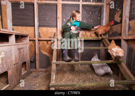 Ragazza giovane con i polli in una capanna di pollo su un blocco di uno stile di vita, proprio fuori Raglan, Nuova Zelanda Foto Stock