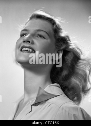 1940s ritratto sorridente giovane donna bionda con testa inclinata indietro il vento che soffia attraverso i capelli Foto Stock