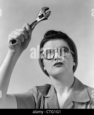 1940s Rosie la rivettatrice indossando occhiali di sicurezza tenendo in mano la chiave di scimmia Foto Stock