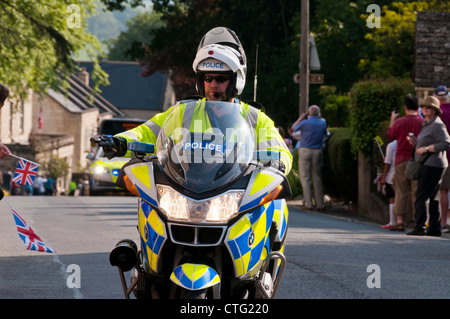 Motociclo funzionario di polizia davanti a torcia olimpica bearer, Painswick, Gloucestershire, Regno Unito Foto Stock