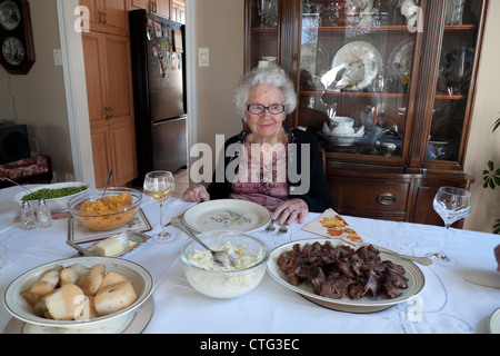 Un anziano sorridente donna senior seduti ad un tavolo da pranzo in attesa per i membri della famiglia ad unirsi a lei in Ontario Canada KATHY DEWITT Foto Stock