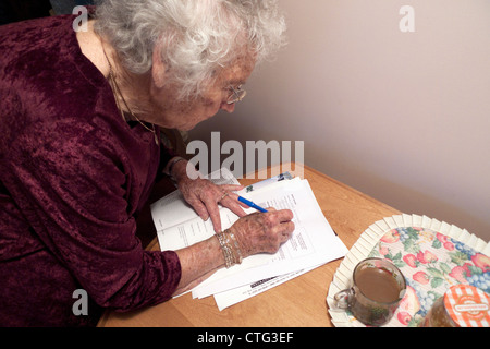 Donna anziana attiva, pensionata di età compresa tra i 90 anni, che firma documenti legali a casa in Canada, KATHY DEWITT Foto Stock