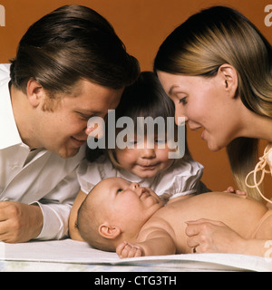 Negli anni sessanta la famiglia guardando al nuovo bambino madre padre sorella Foto Stock