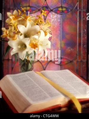 Degli anni Ottanta la molla bouquet di gigli e narcisi con una Bibbia aperta dalla finestra di vetro colorato Foto Stock
