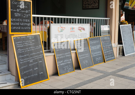 Menu scritto su lavagne a uno spagnolo ristorante sul mare in inglese e tedesco Foto Stock