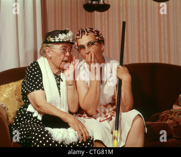 Anni sessanta due senior donne anziane seduto sul divano spettegolare Foto Stock