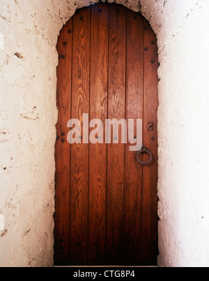 Antiquariato in legno ad arco porta nella parete in stucco Foto Stock