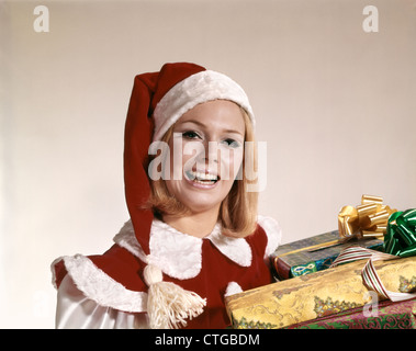 Anni sessanta retrò donna CHRISTMAS SANTA COSTUME HELPER ritratto sorridente doni di contenimento Foto Stock