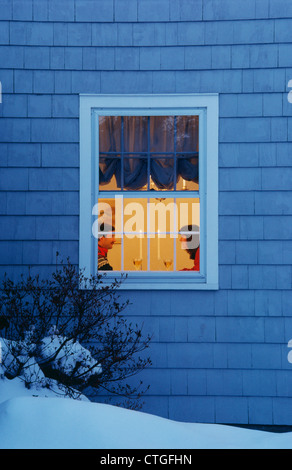 Giovane cenare all'interno in una fredda notte nevosa Foto Stock