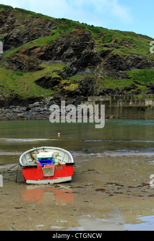 Una barca a remi a Port Issac Harbour, Cornwall a bassa marea con le colline in background Foto Stock