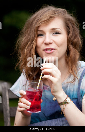Attraente giovane donna di bere un cocktail in un party, REGNO UNITO Foto Stock