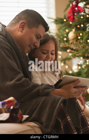 Padre e figlia guardando digitale compressa la mattina di Natale Foto Stock