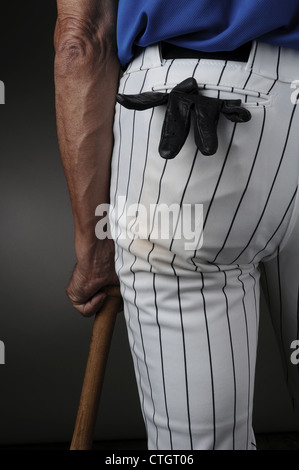 Vista dettagliata del giocatore di baseball visto da dietro e appoggiate su di un legno bat. L uomo è irriconoscibile con un guanto di ovatta in tasca. Foto Stock