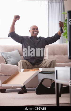 Uomo nero il tifo alla televisione e mangiare la pizza Foto Stock