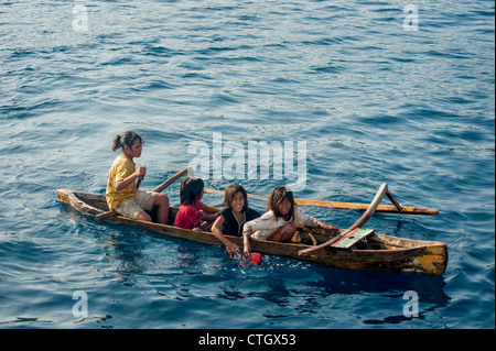 Bambini indonesiano in una piroga canoa outrigger racchetta fino a perle seil ai turisti che sono ancorate al largo di Isola di Komodo, Indonesia. Foto Stock