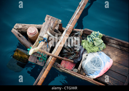 Un pescatore indonesiano in una piroga tradizionale outrigger vende pesce per il cuoco a bordo di una barca a vela. Foto Stock