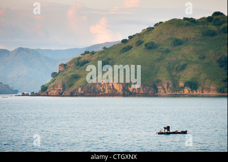 Un pescatore in un tradizionale outrigger funziona l'oceano vicino l'isola di Komodo nel Parco Nazionale di Komodo, Indonesia. Foto Stock