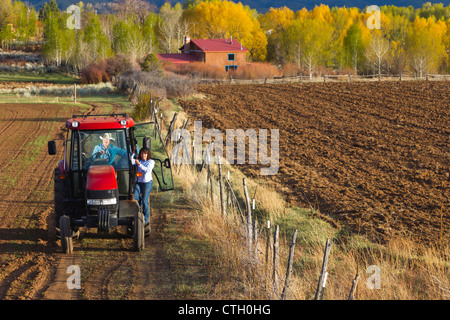 Coppia ispanica di guidare il trattore in agriturismo Foto Stock