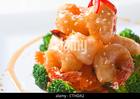 Bistrattato gamberoni su un letto di broccoli cotti al vapore e la carota top con il dolce miele e salsa di semi sasemi. Foto Stock