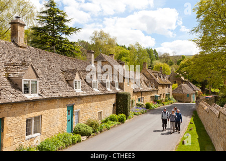 Gli escursionisti che si godono i cottage di pietra accanto al vicolo nel villaggio di Cotswold di Snowshill, Gloucestershire UK Foto Stock