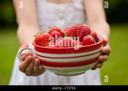 Close-up di mani tenendo una ciotola di fresche fragole mature Foto Stock