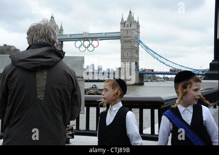 Due ebrei ortodossi boys fermare a guardare un uomo di dipingere un quadro del Tower Bridge di Londra. Foto Stock