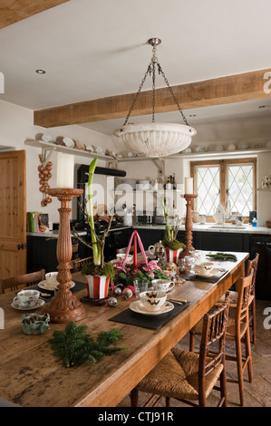 Laid farmhouse table (from Lantique) in cottage kitchen with beamed ceiling and alabaster pendant light Foto Stock