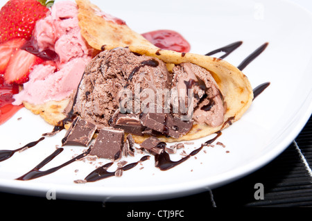 Miscelato di fragole e gelato al cioccolato su una piastra su sfondo nero Foto Stock