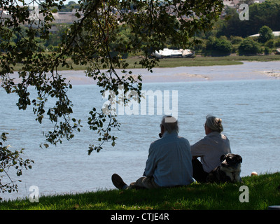 Vecchia coppia e cane seduti sulla riva del fiume, Devon, Regno Unito Foto Stock