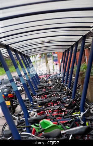 Le biciclette parcheggiate undercover saldamente in una area di parcheggio al di fuori di una stazione ferroviaria in Inghilterra. Foto Stock