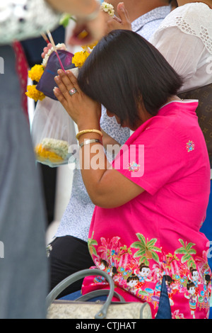 Donna orante presso il Tempio del Buddha di Smeraldo situato entro il perimetro del Grand Palace, Bangkok, Thailandia. Foto Stock