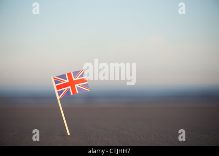 Union Jack flag bloccato in una spiaggia a sunrise. Messa a fuoco selettiva Foto Stock