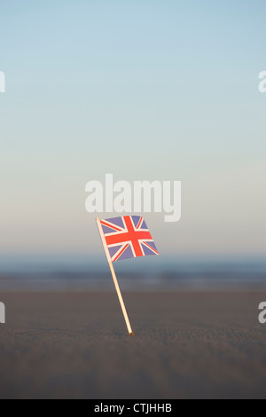 Union Jack flag bloccato in una spiaggia a sunrise. Messa a fuoco selettiva Foto Stock