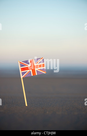 Union Jack flag bloccato in una spiaggia a sunrise. Messa a fuoco selettiva Foto Stock