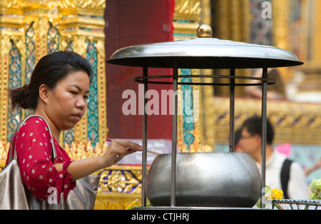 Illuminazione donna incenso presso il Tempio del Buddha di Smeraldo situato entro il perimetro del Grand Palace, Bangkok, Thailandia. Foto Stock