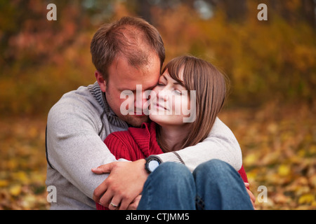 I giovani coniugi abbracciando intimamente in un parco in autunno; Edmonton Alberta Canada Foto Stock