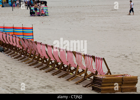 Striping tradizionale sdraio del vuoto in una fila sulla spiaggia Foto Stock