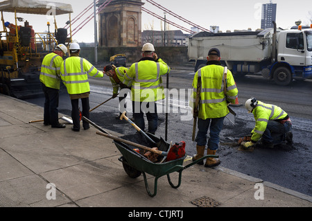 Lavoratori la riparazione della superficie stradale con asfalto, Glasgow, Scotland, Regno Unito, Gran Bretagna Foto Stock